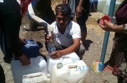 Salah satu relawan tampak merekayasa botol air mineral jadi torong agar air bisa masuk ke jurigen (Foto : Istimewa / TulungagungTIMES)
