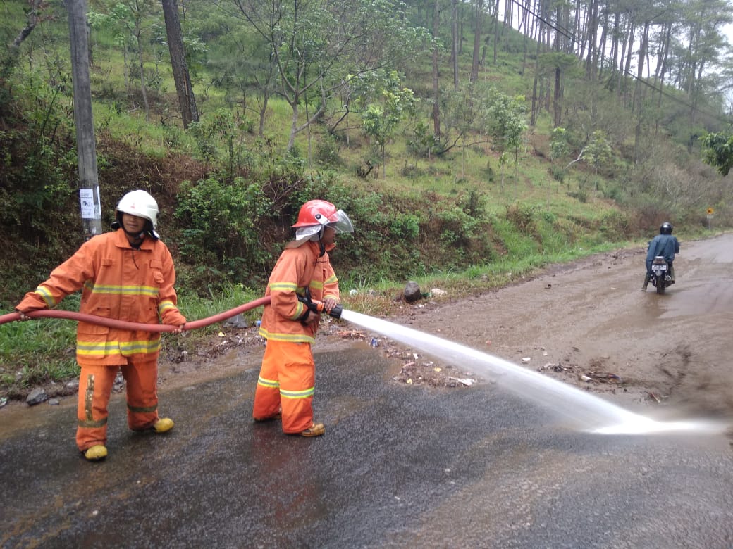 Para petugas tengah membersihkan jalan di Kota Batu yang tergenang lumpur dan sampah usai hujan deras. (Foto: BPBD Kota Batu for MalangTIMES)