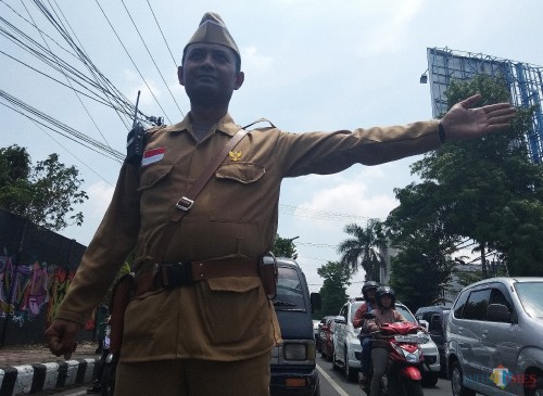 Salah satu petugas mengenakan kostum pejuang sedang mengatur lalu lintas. (eko Arif s/JatimTimes)