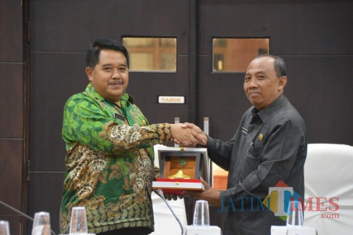 Kepala Bakesbangpol Trenggalek bersama dengan Asisten Pemerintahan Pemkab Jember saat bertukar cindera mata (foto : istimewa / Jatim TIMES)