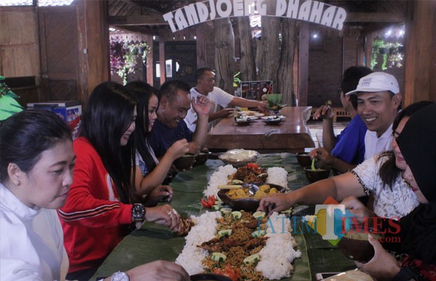 Caption gambar : Sri Hariyati (47), pengunjung asal Kabupaten Malang, saat menikmati Sego Bancakan bersama keluarganya di rumah makan Waroeng Tandjoeng Dhahar. (Foto : Adi Rosul / JombangTIMES)