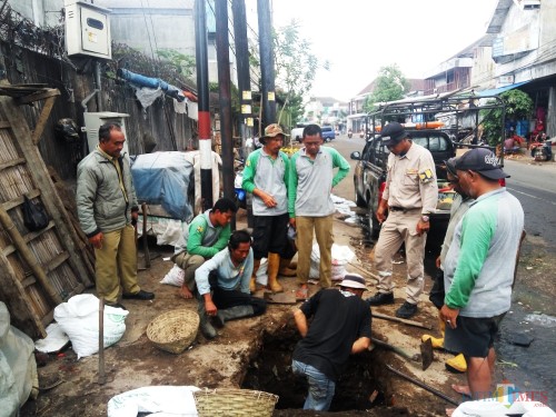 Satgas saat melakukan pembersihan gorong-gorong yang tersumbat sampah akibat menyangkut di tiang provider. (Anggara Sudiongko/MalangTIMES)