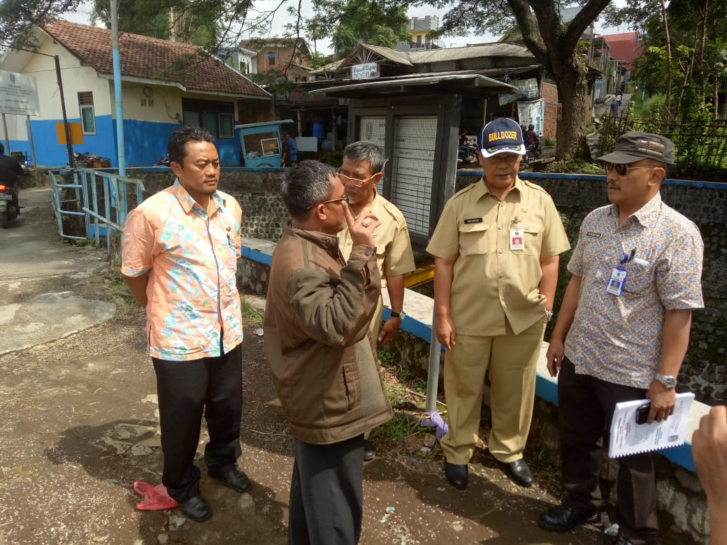 Kepala DPUPR Kota Malang Hadi Santoso (mengenakan topi) saat melakukan pengecekan lokasi pintu air di sungai yang mengarah ke wilayah Kota Malang. (Foto: DPUPR Kota Malang for MalangTIMES)