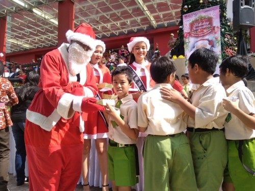 Santa Claus membagikan makanan kepada siswa SD di Matos.