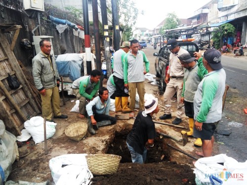 Petugas saat melakukan pembersihan saluran melalui bak kontrol. (Anggara Sudiongko/MalangTIMES)