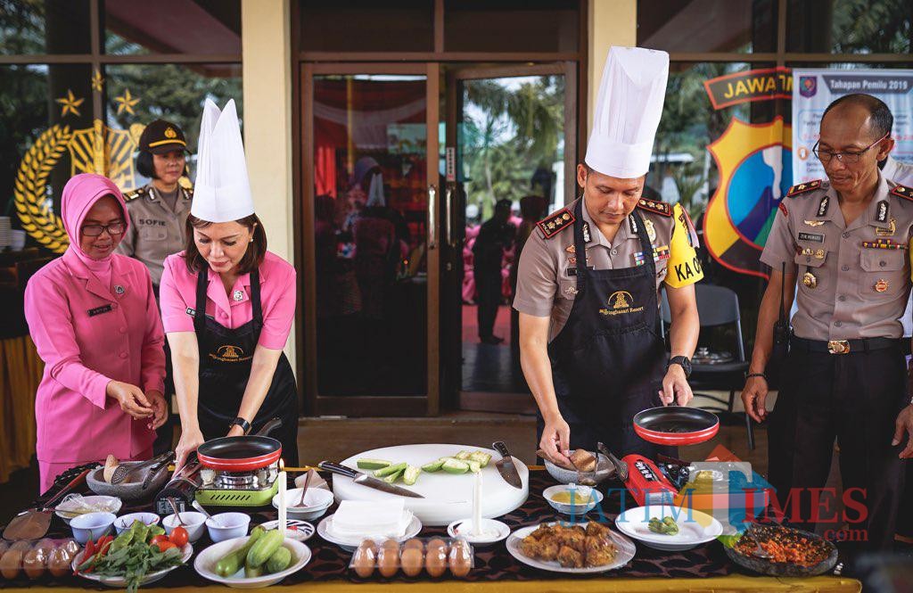 Kapolres Batu AKBP Hermanto (kanan) bersama Ketua Bhayangkari Kota Batu Enic Budi Hermanto saat memasak di halaman Polres Batu, Senin (14/1/2019). (Foto: istimewa)
