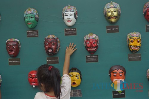 Seorang anak kecil yang bermain di sekitar display topeng. Foto : Agung Wardoyo untuk JatimTIMES