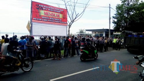 warga memasang baliho di dekat pintu masuk menuju area reklamasi