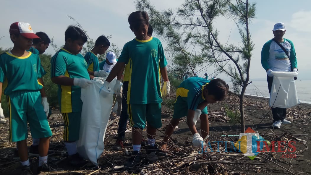 para pelajar SD sedang memungut sampah di kawasan pantai Cemara