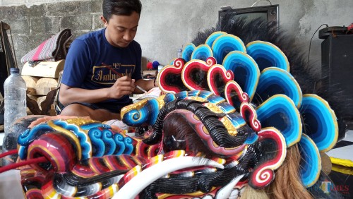 Putut saat mengecat barongan yang dibuatnya sebelum dikirim ke pemesan (foto: Joko Pramono/Jatim Times)