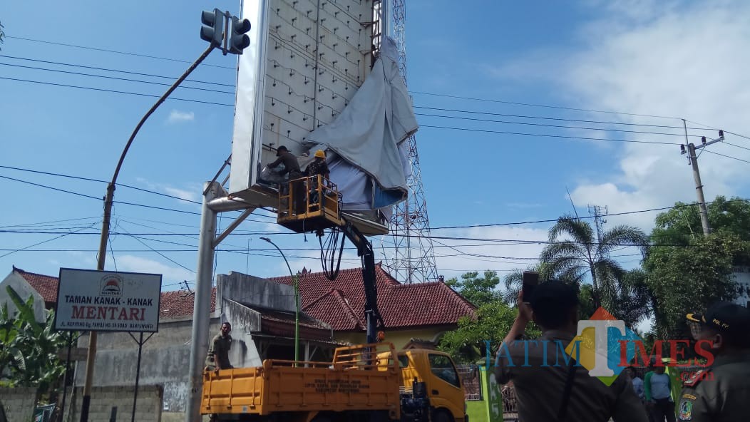 Petugas Satpol PP dan Bawaslu membuka APK yang terpasang di sekitar patung kuda, Karangente Banyuwangi.