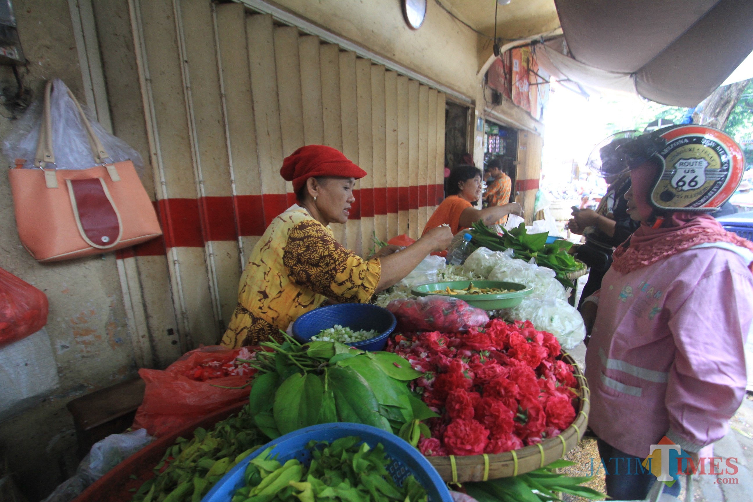Sanema, pedagang bunga di trotoar depan Pasa baru, sedang melayani pembeli (Agus Salam/Jatim TIMES)