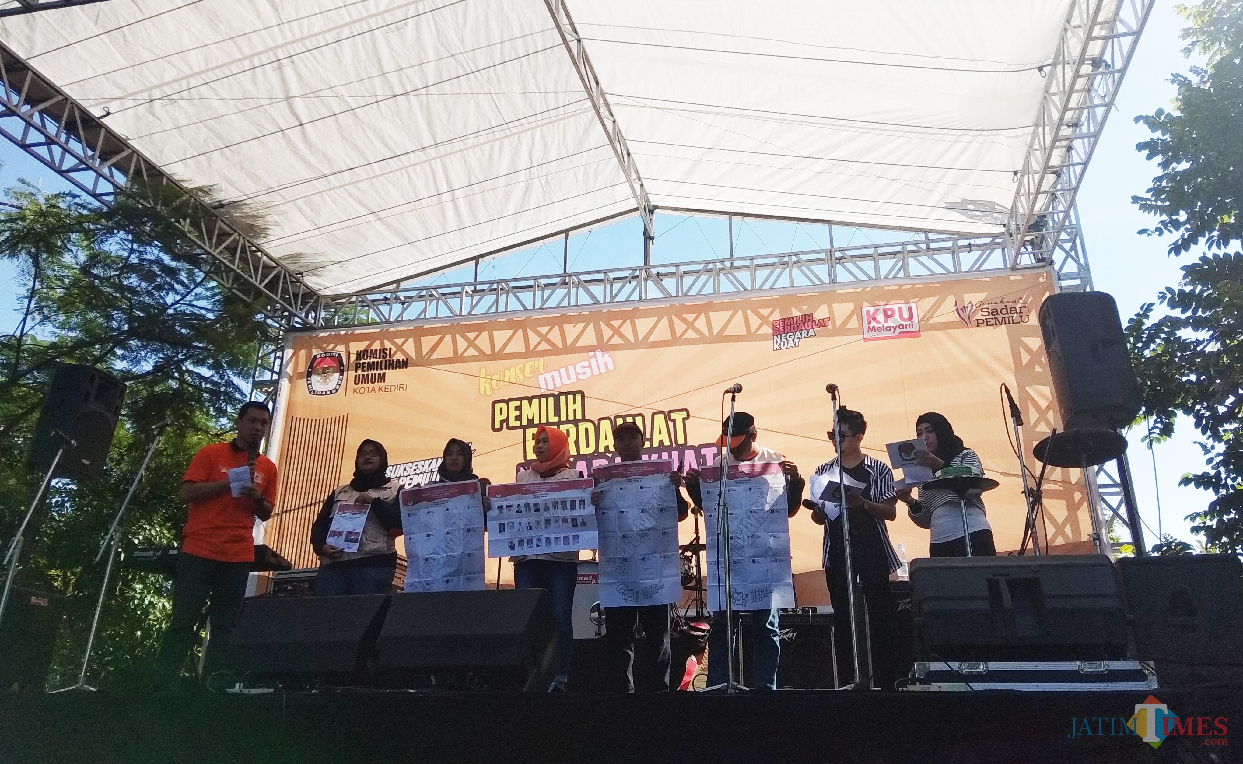 Para anggota KPU saat memberikan contoh surat suara kepada masyarakat dalam acara konser musik. (eko Arif s /JatimTimes)