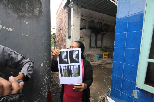 Yuli Era menunjukkan foto jalan kecil yang ditutup dengan sesek bambu di jalan oleh keluarga Sanali (Agus Salam/JatimTIMES)