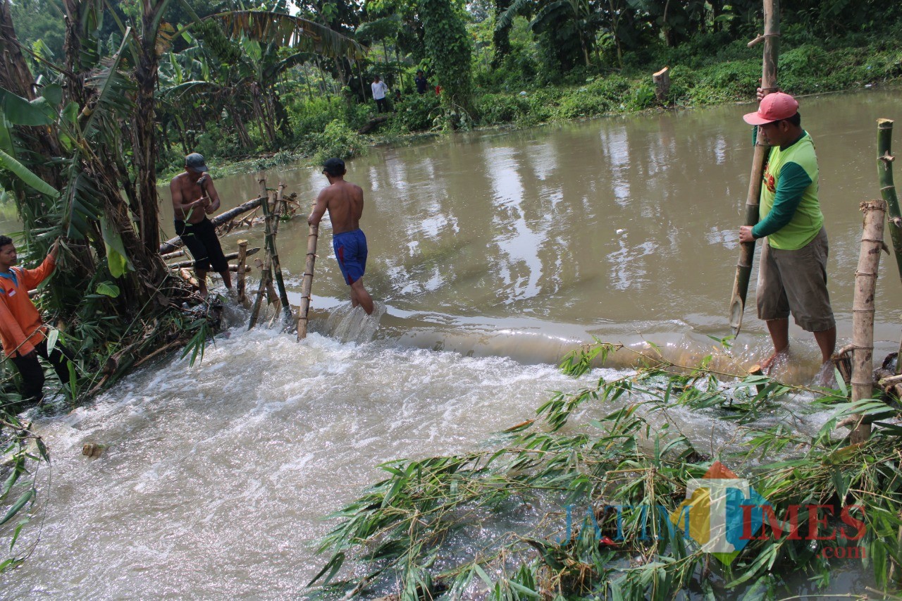 Sejumlah warga Desa Kedunglosari tampak bergotong-royong membendung tanggul yang jebol. (Foto : Adi Rosul / JombangTIMES)