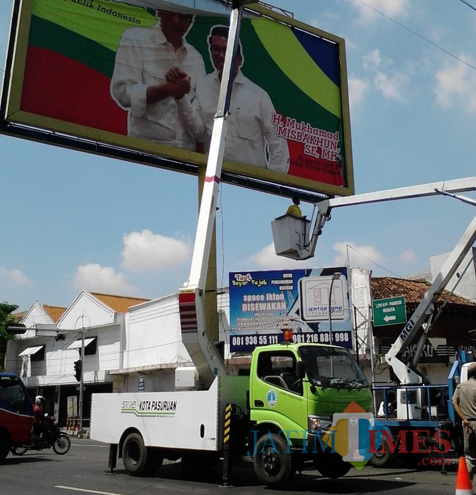 Petugas mencopot baliho bergambar presiden dan anggota DPRRI.