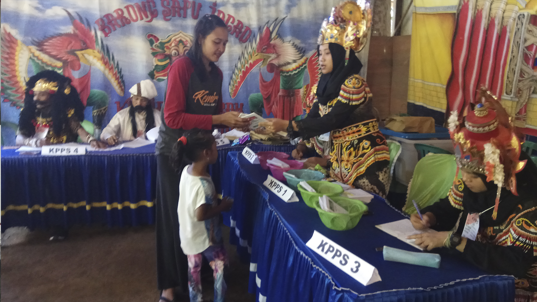 Petugas KPPS mengenakan kostum Barong untuk menarik minat masyarakat datang ke TPS