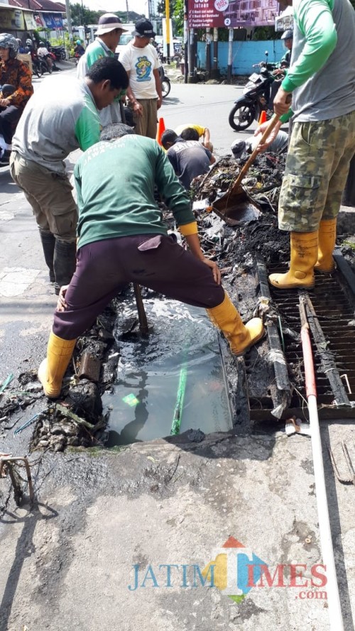 Suasana Satgas DPUPR saat membersihkan saluran yang tertimbun sampah (Hendra Saputra/ MalangTIMES)
