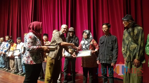 Seniman tradisi asal Malang, Sumanah saat menerima piagam penghargaan dari Sekda Pemprov Jatim Heru Tjahjono. (Foto: Dokumen MalangTIMES)