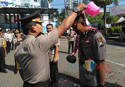 Kapolres AKBP Tofik Sukendar mengguyur air kembang pada Kompol Ki Ide Bagus Tri dalam Sertijab (foto : Anang Basso / TulungagungTIMES)