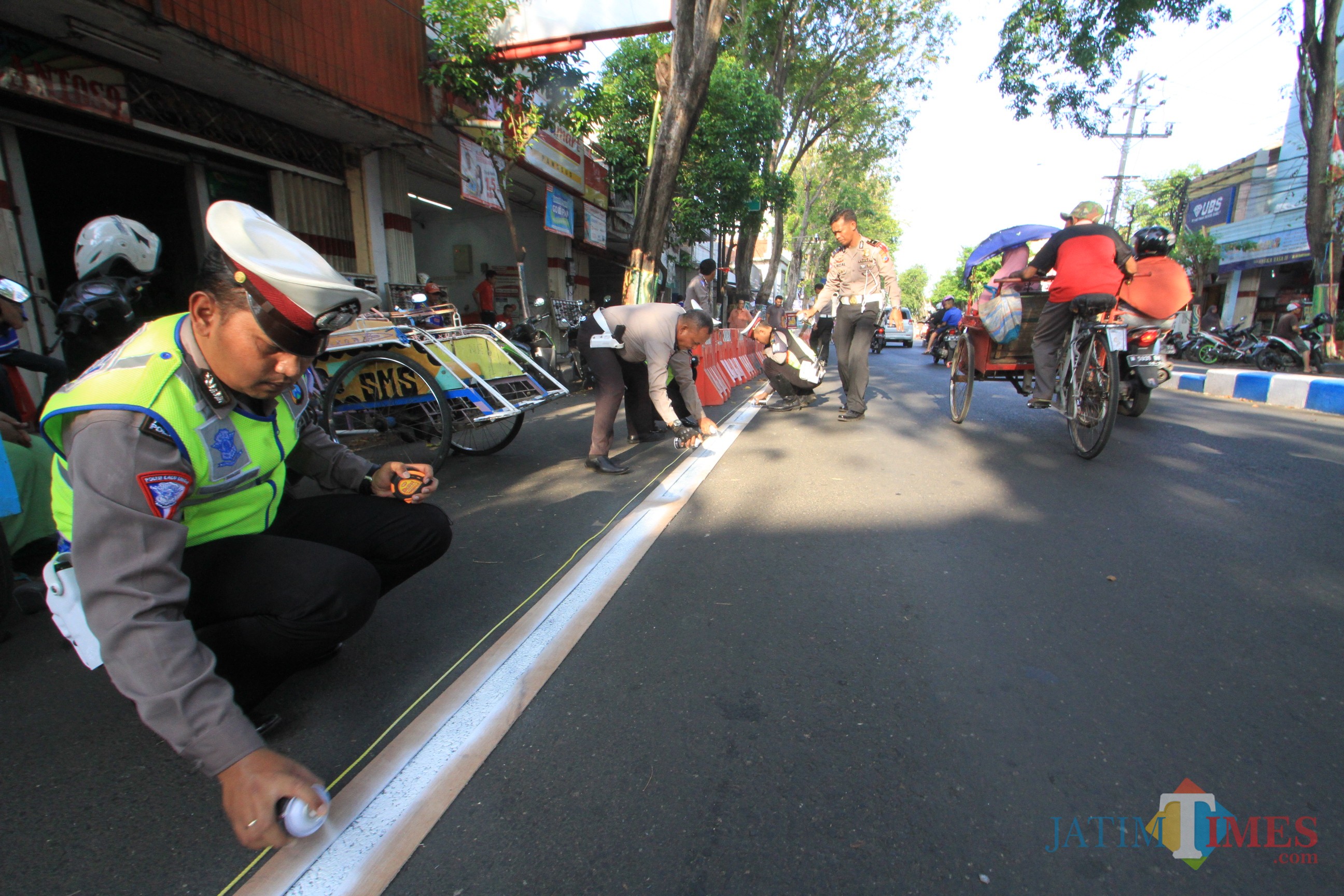 Petugas Satlantas tengah mengecat pembatas parkir (Agus Salam/Jatim TIMES)