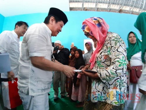 Komisaris PT ACA Iwan Kurniawan (kopyah Hitam) memberikan santunan kepada duafa di Balai Desa Pagak, Kabupaten Malang. (Foto:Hezza Sukmasita/MalangTIMES)
