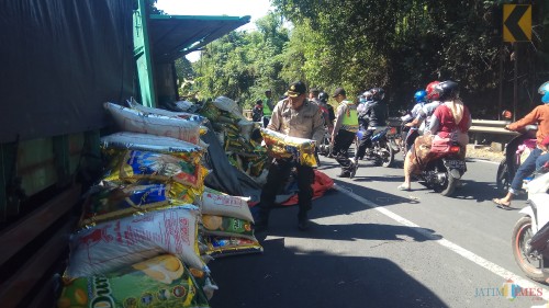Petugas kepolisian memindahkan beras yang berada di badan jalan.