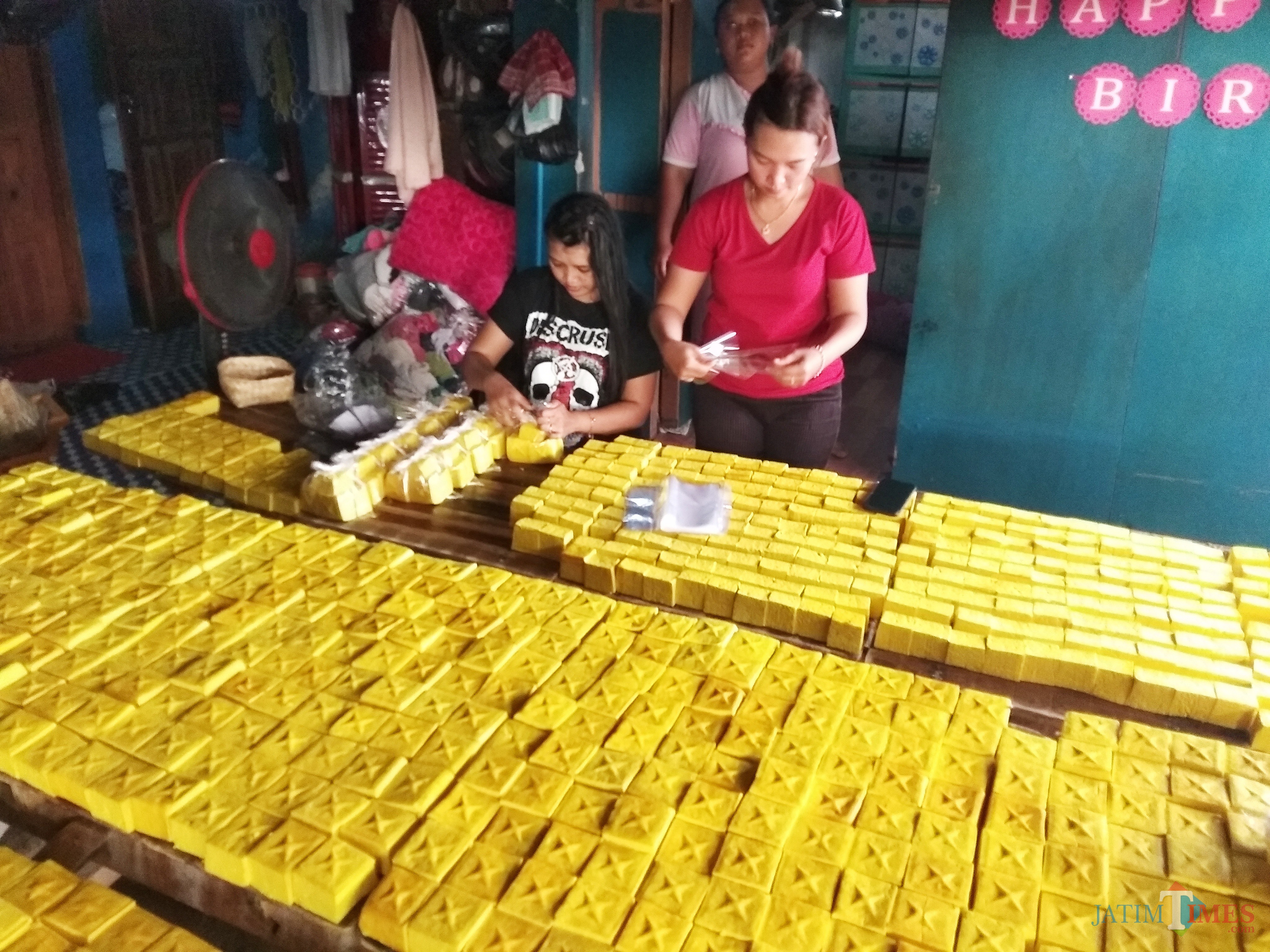 Purborini (baju merah) saat mengenakan tahu yang baru di produksi. (eko Arif s /JatimTimes)