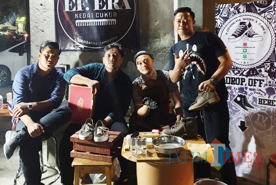 Aderay Putra Perdana (kanan) saat membersihkan sepatu milik customer. (eko Arif s /JatimTimes)