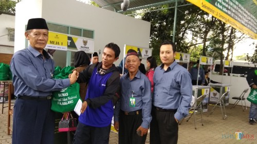 Kepala Baznas Kota Malang Sapardi menyerahkan paket santunan secara simbolis pada tenaga honorer. (Foto: Nurlayla Ratri/MalangTIMES)