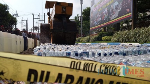 Alat berat digunakan untuk menggilas ribuan miras hasil Operasi Pekat Semeru 2019. / Foto : Anang Basso / Tulungagung TIMES