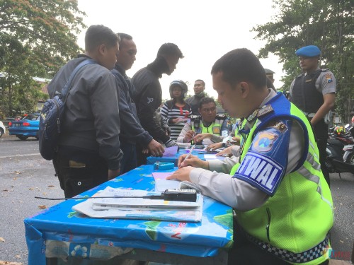 Petugas kepolisian saat memberikan surat tilang kepada pengguna jalan karena tidak memiliki SIM. (Foto : Ashaq Lupito / MalangTIMES)