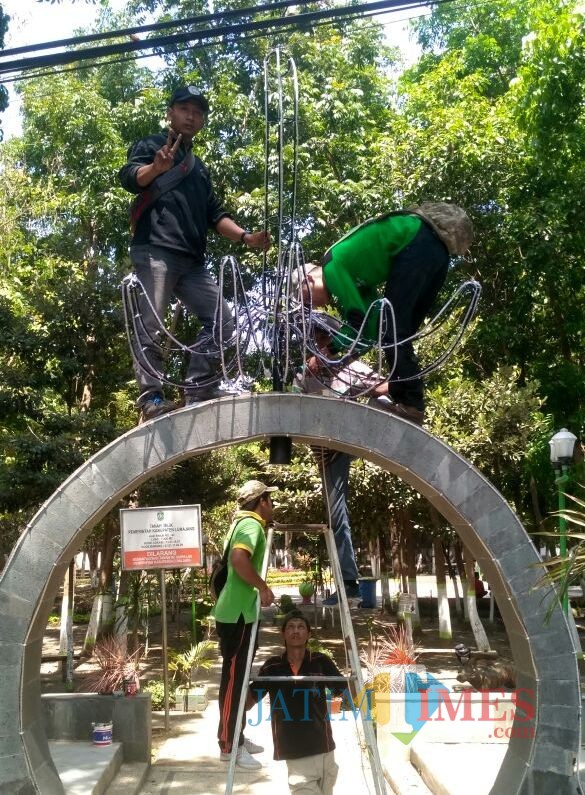 Petugas dari DLH ketika memperbaiki lampu hutan kota pasca dirusak warga (Foto : Moch. R. Abdul Fatah / Jatim TIMES