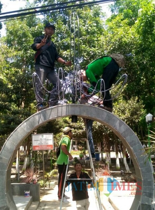 Petugas dari DLH ketika memperbaiki lampu hutan kota pasca dirusak warga (Foto : Moch. R. Abdul Fatah / Jatim TIMES