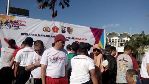 Beberapa warga saat bergantian membubuhkan tanda tangan di banner deklarasi masyarakat Jember tolak kerusuhan. (foto : Moh. Ali Makrus / Jatim TIMES)