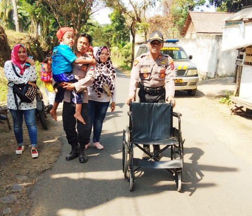Kapolsek Giri Iptu Suryono Bhakti, bersama seorang anggota Bhabinkamtibmas saat membantu seorang bocah penderita hidrocephalus