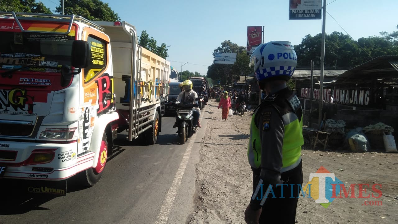 Anggota Satlantas Polres Lumajang yang berusaha mengurai kemacetan di rusa jalan Klakah Wonorejo (Foto : Moch. R. Abdul Fatah / Jatim TIMES)