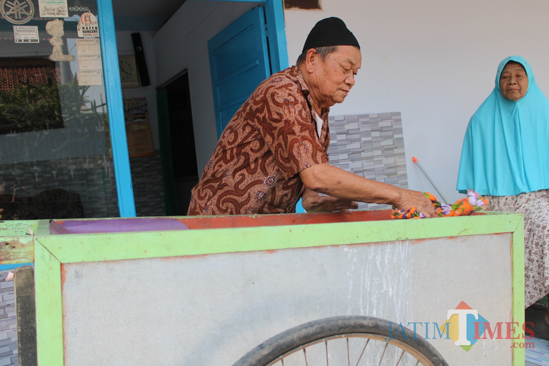 Samsuri saat membersihkan gerobak yang sehari-hari digunakan berjualan bubur. (Foto : Adi Rosul / JombangTIMES)