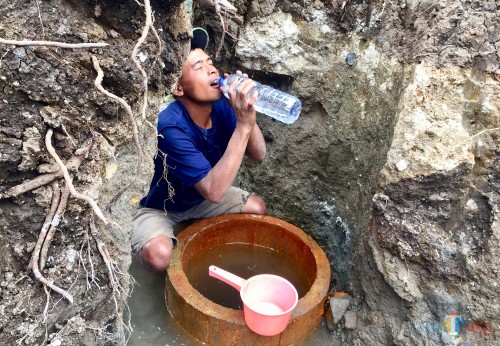 Warga saat menyiduk air sumber air hangat di Sumber Nyi Sindu Dusun Sumbersari, Desa Sumberejo, Kecamatan Batu, Kamis (11/7/2019). (Foto: Irsya Richa/MalangTIMES)