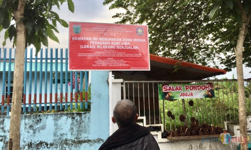 Salah satu warga saat melihat papan larangan berjualan di zona merah di Jalan Panglima Sudirman. (Foto: Irsya Richa/MalangTIMES)