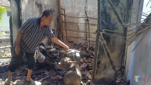 Edi Suprianto tengah membersihkan puing-puing bengkelnya setelah terbakar Selasa dini hari (Agus Salam/JatimTIMES)
