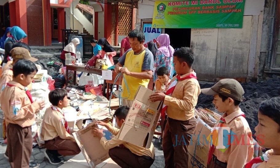 Para wali murid dan murid sedang mengemas sampah belas di halaman MI Darul Ulum Batu.