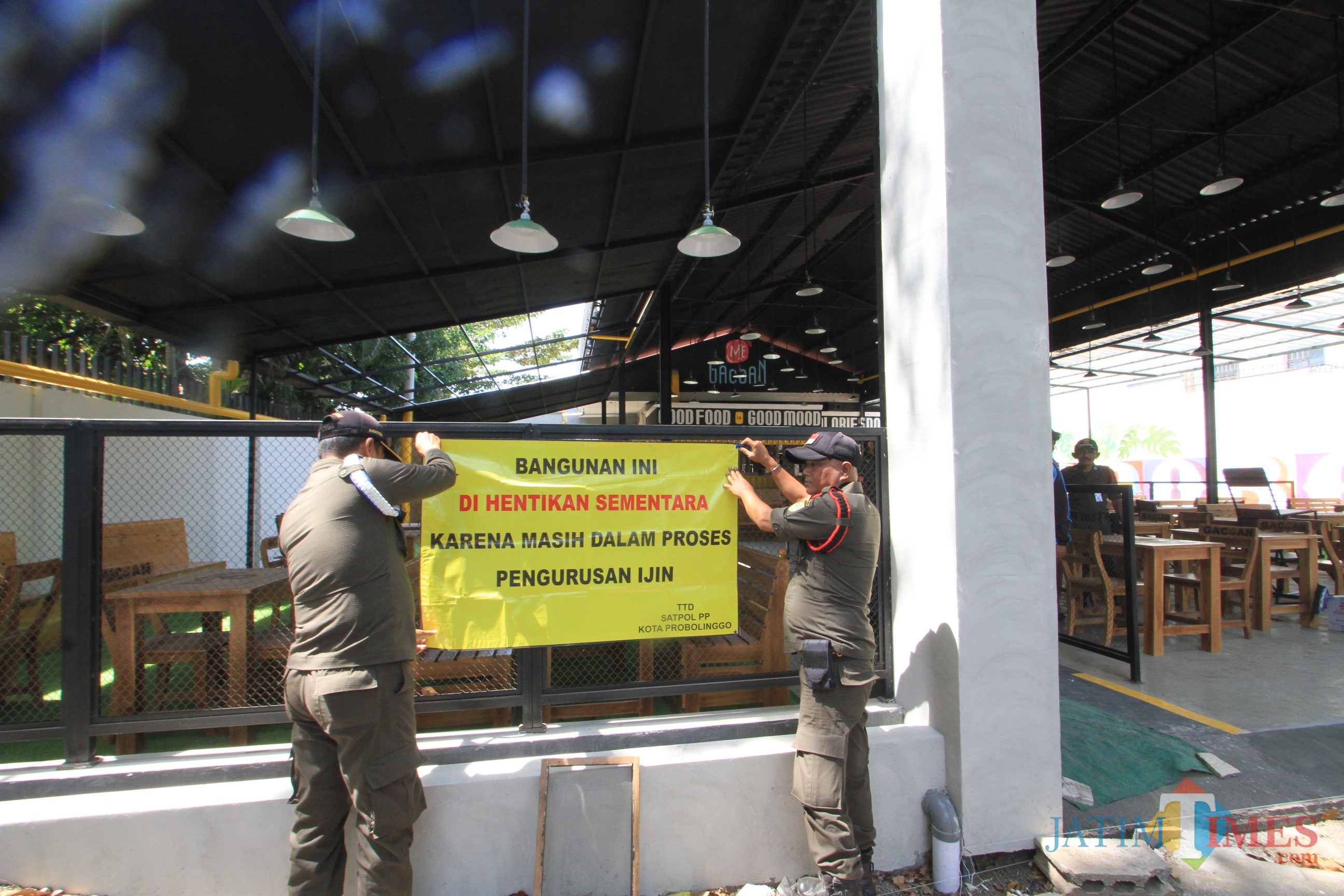 Petugas Satpol PP tengah memasang spandulkk penutupan warung mie di jalan Suroyo, Kota Probolinggo (Agus Salam/Jatim TIMES)