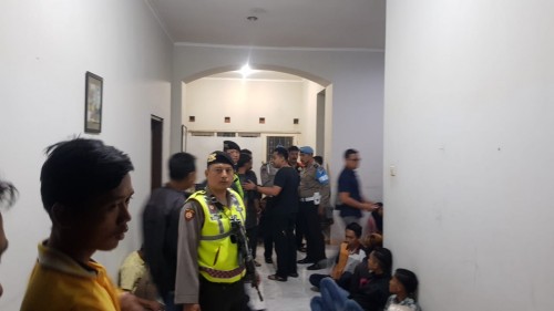 Polisi saat melakukan penggerebekan sebuah rumah yang ditempatkan member Q net. (Ist)