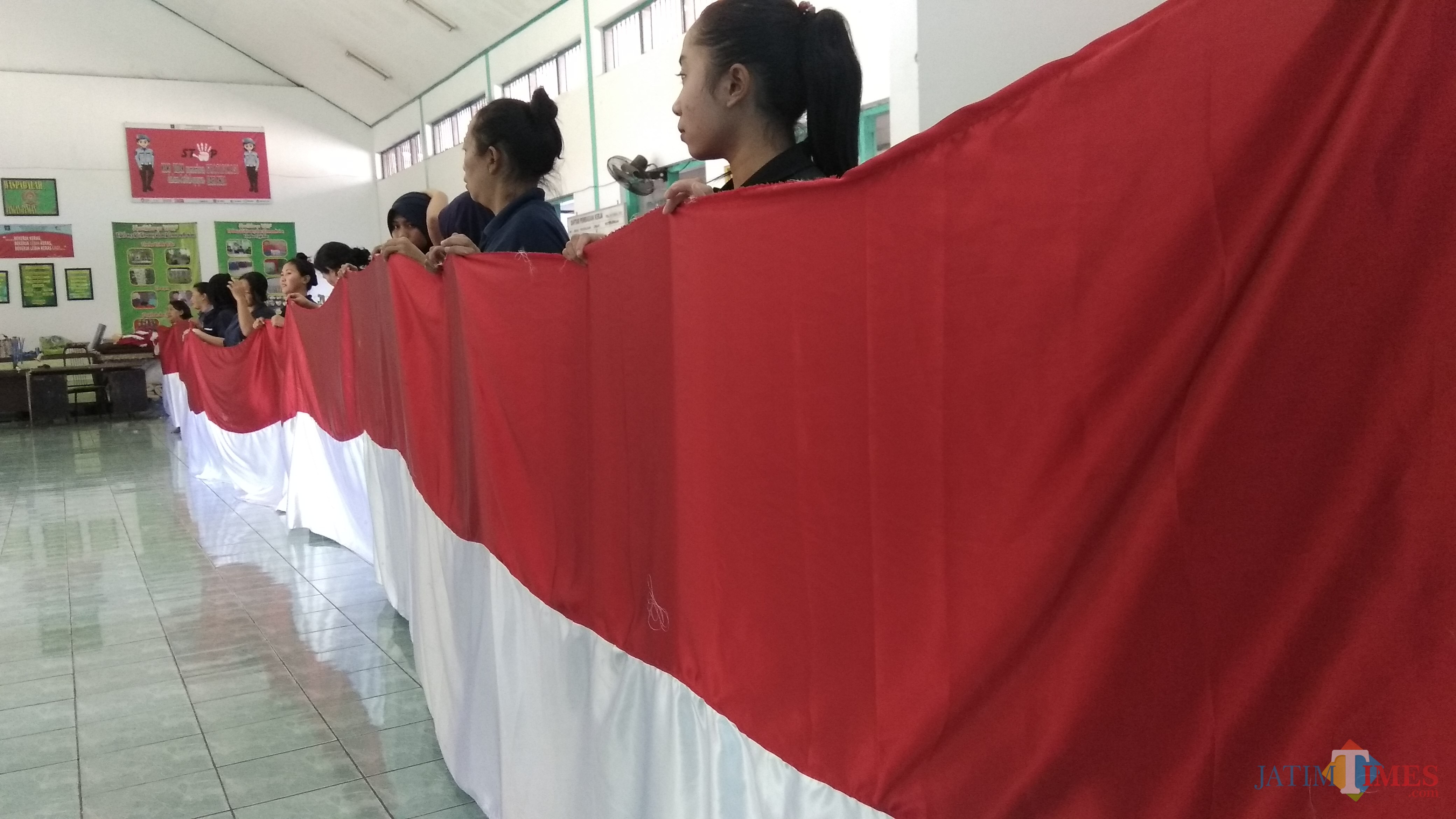 Para warga binaan pemasyarakatan Lapas Wanita Klas IIA Sukun Malang saat menggelar sebagian hasil jahitan bendera raksasa. (Foto: Nurlayla Ratri/MalangTIMES)
