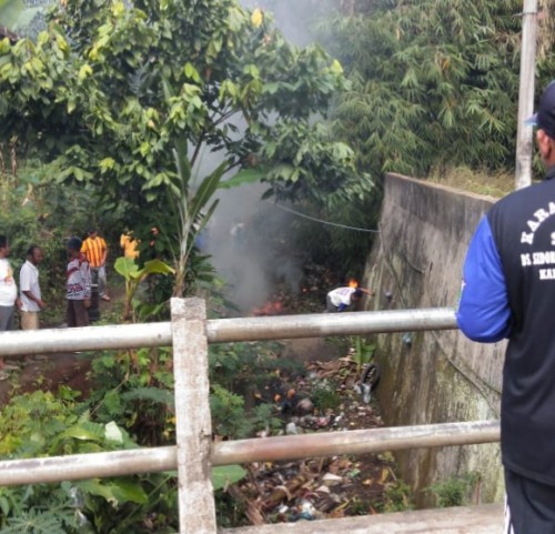 warga bersama KKN Unikama saat membersihkan dan membakar sampah di bawah jembatan yang dialiri Sungai Jagalan (Unikama for MalangTIMES)