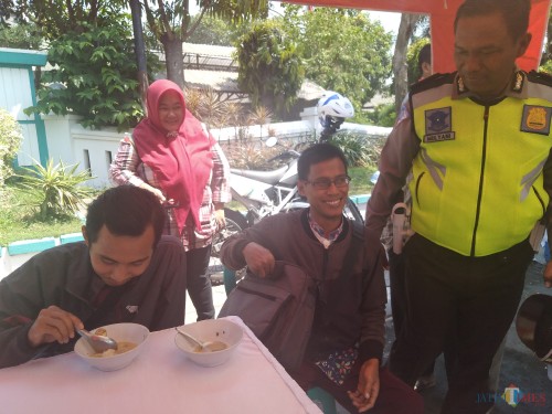Kanit Turjawli Satlantas Polres Jombang, Iptu Mulyani terlihat ngobrol dengan pelanggar yang sedang menikmati bubur yang disediakan oleh pihak Satlantas. (Foto : Adi Rosul / JombangTIMES)
