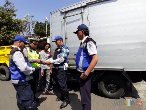 Petugas saat memeriksa kelengkapan surat-surat kendaraan dalam operasi gabungan (Arifina Cahyanti Firdausi/MalangTIMES)