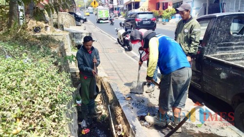 Petugas DPUPR Kota Batu saat mengangkat sampah yang ada di dalam saluran drainase dan gorong di Jalan Panglima Sudirman sebelum musim hujan.