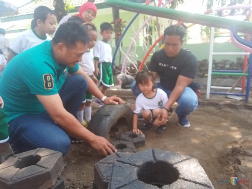Kabid SDA Bambang Nugroho dan Pasi Intel Kodim 0833 Kapten Arh Imron bersama murid TK Kartika V 77 melakukan pemasangan paving secara simbolis. (Anggara Sudiongko/MalangTIMES)